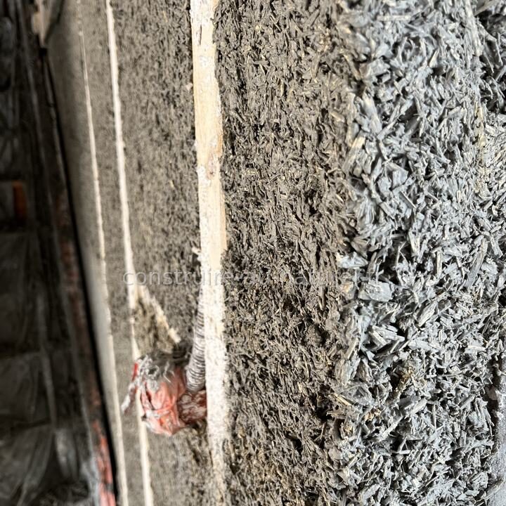 Gros plan sur le béton de chanvre tassé à la main entre deux montants